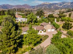 an aerial view of a home surrounded by trees, mountains and hills in the distance