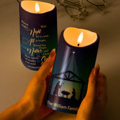 two candles with the nativity scene on them being held by someone's hands