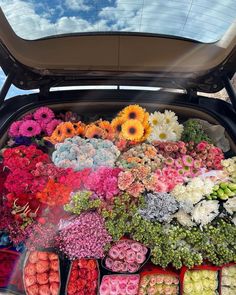 the trunk of a car filled with lots of flowers