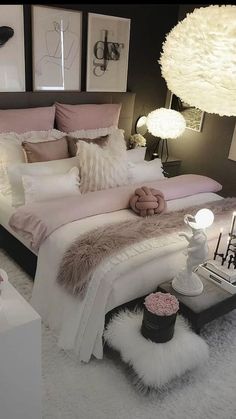 a bed with pink and white comforters, pillows and candles on the end tables