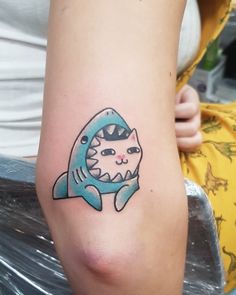 a person with a tattoo on their arm that has a cat in a shark's mouth