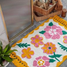 a bathroom rug with flowers on it next to an open door and potted plant