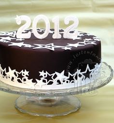 a chocolate cake with white frosting and stars on top is sitting on a glass platter