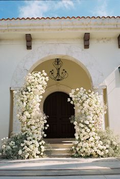 an entrance to a building with white flowers on it