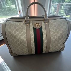 Description: Gucci, Under The Direction Of Alessandro Michele Since 2015, Continues To Reinterpret Its Rich Heritage. This Gucci Gg Supreme Savoy Small Duffle Bag Features The Iconic "Double G" Motif, Symbolizing The Brand’s Balance Between Historical References And Contemporary Style. Perfect For Those Who Value Luxury And Timeless Design. Condition: No Notable Wear. Details: Dimensions: 17.5" W X 10.5" H X 9.5" D Handle Drop: 5" Shoulder Strap Drop: Adjustable, Up To 24" Material: Nylon, Coated Canvas, Leather Color: Beige Lining: Beige Canvas Pockets: Two Interior Hardware: Antique Gold Tone Closure: Double Zip Includes: Detachable Shoulder Strap, Lock & Key, Luggage Tag, Clochette, Interior Hardware, Small Duffle Bag, Bags Gucci, Locks & Key, Alessandro Michele, Gucci Bags, Luggage Tag, Canvas Leather, Luggage Tags