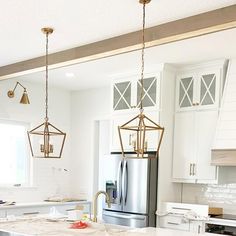 a kitchen with marble counter tops and gold pendant lights hanging from the ceiling over the island