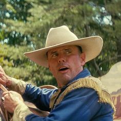 a man wearing a cowboy hat and holding onto a horse's bridle