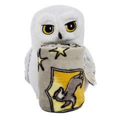 an owl stuffed animal sitting on top of a small pillow with a yellow and white design