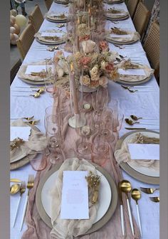 the table is set with gold and white plates, silverware, napkins, and flowers