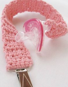 a pink crocheted bracelet with a heart shaped object attached to the wristband