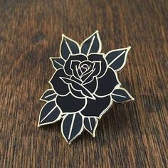 a black and white rose pin sitting on top of a wooden table