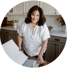 a woman standing in front of a kitchen counter with an open book on top of it