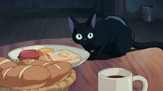 a black cat sitting on top of a wooden table next to a plate of food