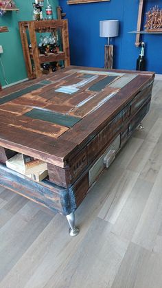 a coffee table made out of pallet wood in a room with blue walls and hardwood floors