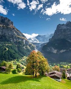 the mountains are covered in snow and green grass, with houses on either side of them