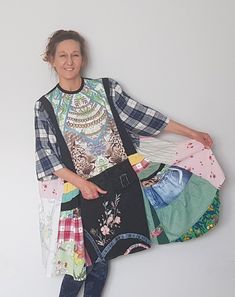 a woman standing in front of a white wall with lots of clothes on her back