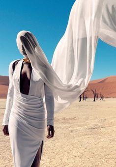 a woman in a white dress is walking through the desert