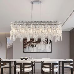 a chandelier hanging from the ceiling in a dining room with white table and chairs