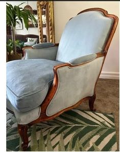 a blue chair sitting on top of a rug in front of a mirror and potted plant