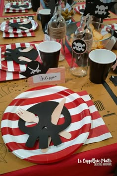 the table is set with pirate themed paper plates and place cards for guests to eat