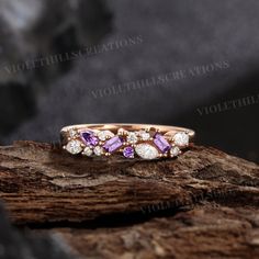 a pink and white diamond ring sitting on top of a tree branch with rocks in the background