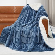 a blue blanket sitting on top of a couch next to a brown leather sofa chair