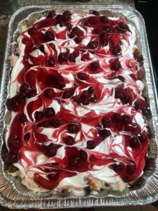 a cake with cherries and white frosting on it in a metal pan sitting on top of a table