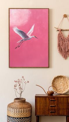 a painting hanging on the wall next to a small table with a basket and vase