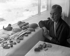 an old woman sitting at a table with rocks on it and other stones in front of her