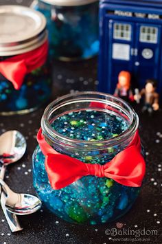 a jar filled with blue and green liquid next to two spoons on top of a table