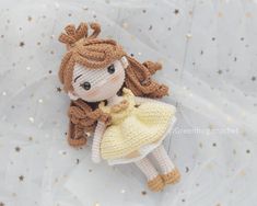 a crocheted doll laying on top of a white sheet with gold glitters