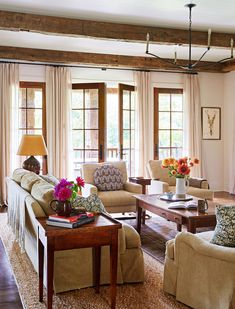 a living room with couches, chairs and coffee table in front of two windows