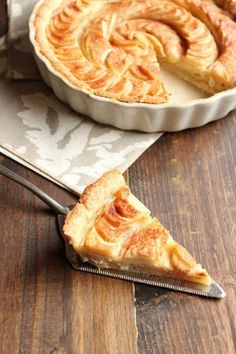 a piece of pie sitting on top of a wooden table next to a knife and fork