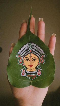 a hand holding a green leaf with an image of a woman's face on it