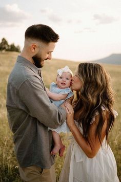 a man and woman holding a baby in a field