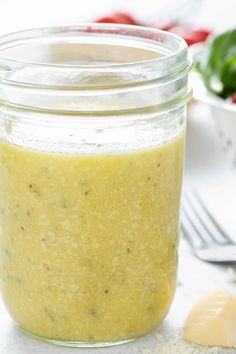 a glass jar filled with green sauce next to a knife and fork