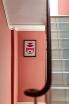 the stairs are painted pink and white in this room with an art work on the wall