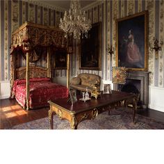 an ornately decorated bedroom with antique furniture and paintings on the walls, along with a chandelier