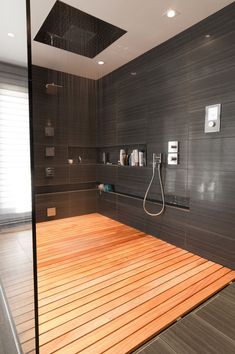 an image of a bathroom with wood flooring and tile on the walls, along with a shower head