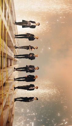 four people standing in front of a building with water reflecting on the ground and sky behind them