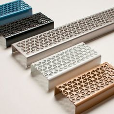 four different colored metal grates sitting on top of a white table next to each other