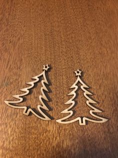 two metal christmas trees sitting on top of a wooden table