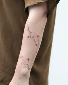 a person with a tattoo on their arm that has flowers growing out of the side