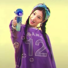 a girl with long hair wearing a purple shirt and holding a blue object in her hand