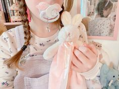 a woman holding a stuffed animal in front of a mirror with other stuffed animals around her