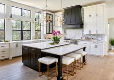 a large kitchen with white cabinets and marble counter tops, along with an island in the middle