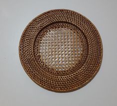 a brown woven plate sitting on top of a white tablecloth covered floor next to a wall