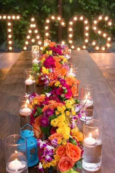 a long table with candles and flowers on it is set up in front of the word love