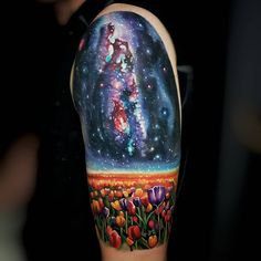 a person with a tattoo on their arm that has flowers and stars in the sky