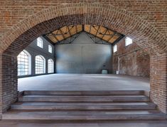 an empty room with brick walls and steps leading up to the second floor that is surrounded by windows